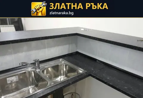 Две метални корита са вградени в тъмен ъглов плот над отворена долна зона с видими тръби