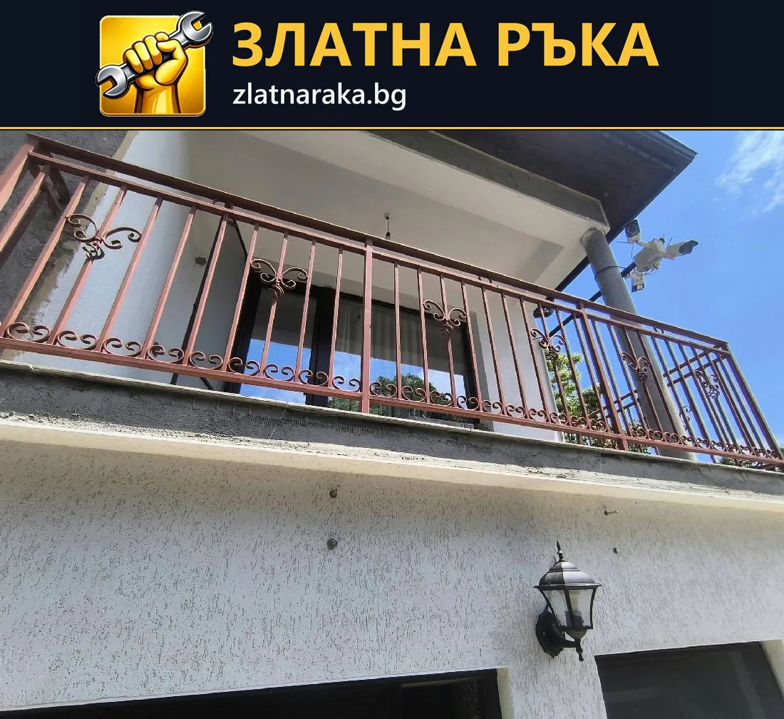 Червеникав метален парапет с вертикални пръти върху бяла фасада