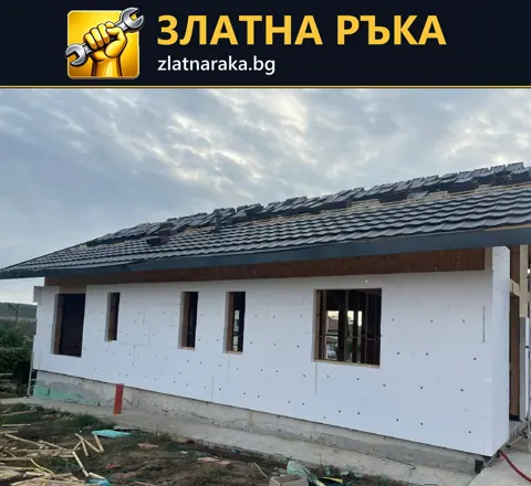 Дълга фасада с монтирани бели изолационни плочи, видими закрепвания и незавършени прозоречни отвори