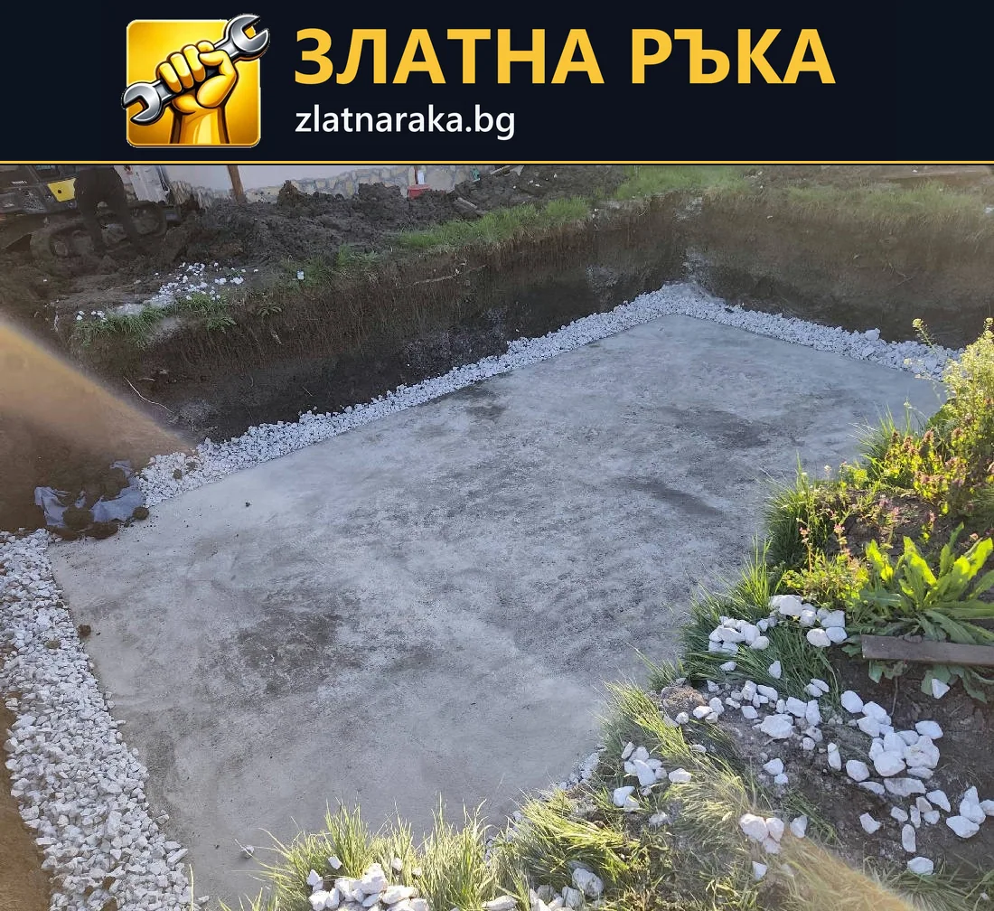 Правоъгълна сива площадка в двор е обрамчена с бял чакъл до тревни и цветни участъци