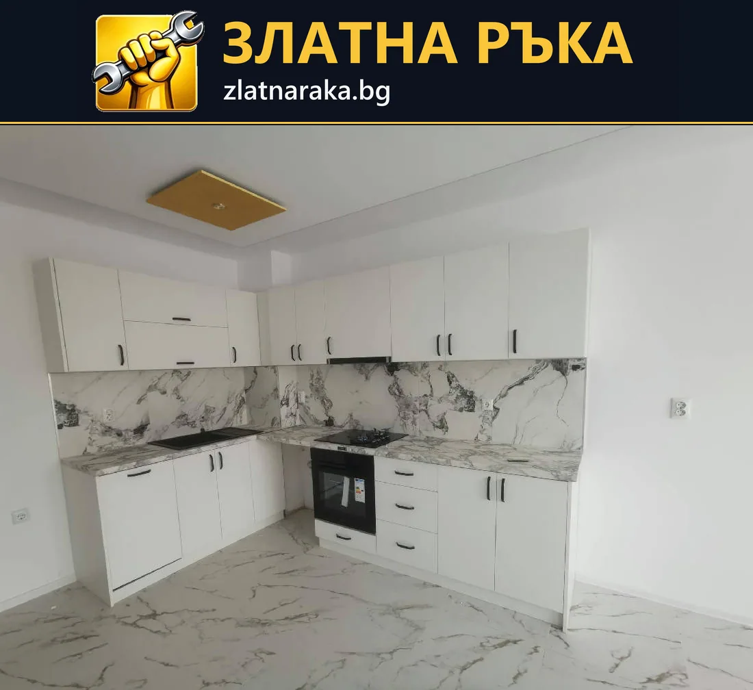 Бяла ъглова кухня с черна фурна, светъл плот и контрастна мраморна шарка
