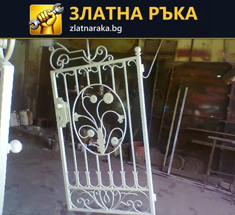 Бяло метално пано с вертикални пръти, извити орнаменти и листа в работилница.