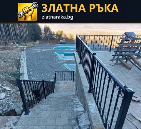 Каменни външни стъпала между черни метални парапети слизат от тераса към по-нисък двор