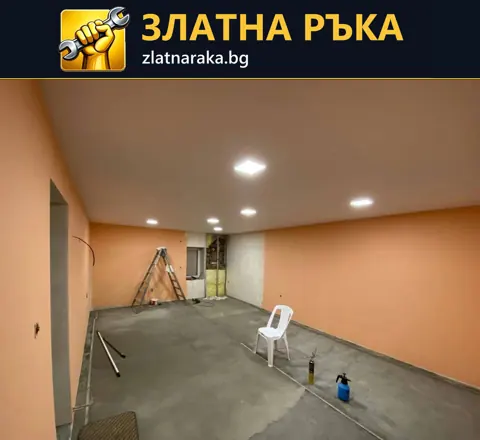 Помещение с топли оранжеви стени, светъл таван с лампи и незавършен сив под