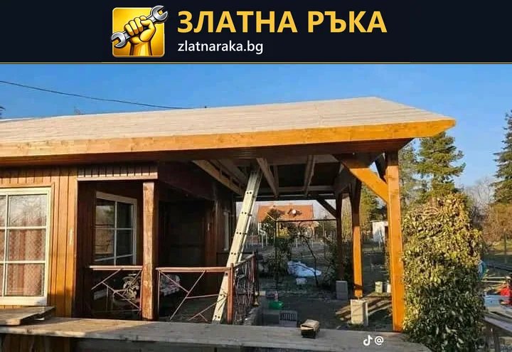 Дървена постройка с остъклени врати и широка предна греда има недовършена покрита веранда със стълба