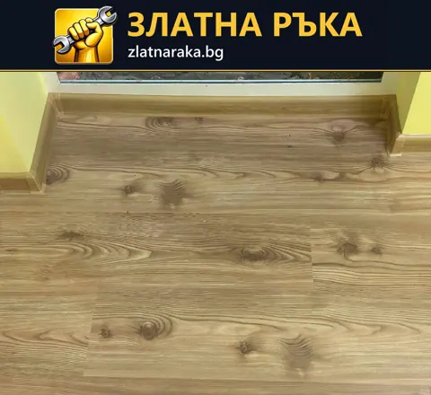 Детайл на дървесна подова настилка и первази около праг с жълти стени.