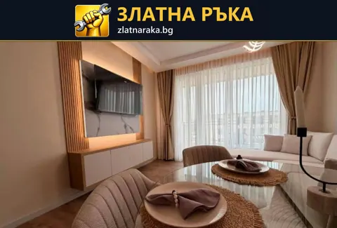 Светла дневна с телевизор върху декоративно пано, нисък шкаф, маса и завеси.