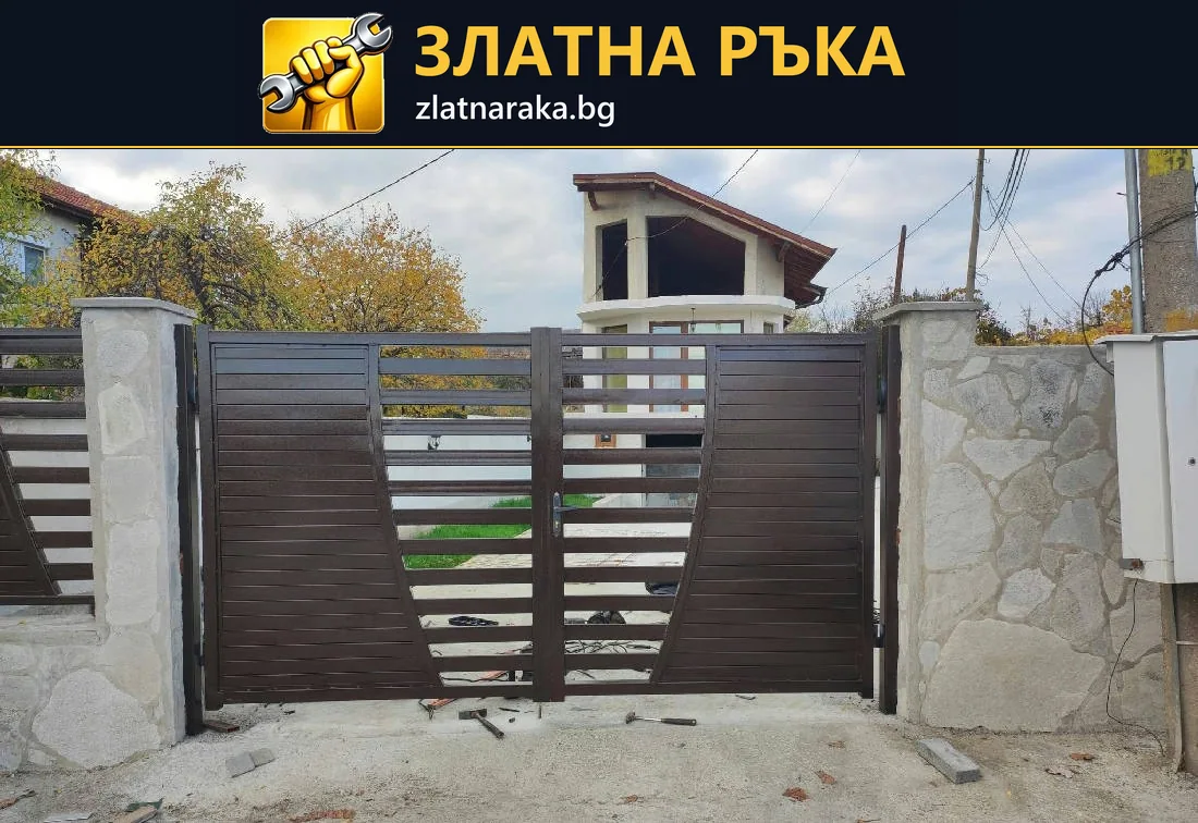 Тъмна двукрила порта с хоризонтални ламели между светли колони и ограда с каменна облицовка