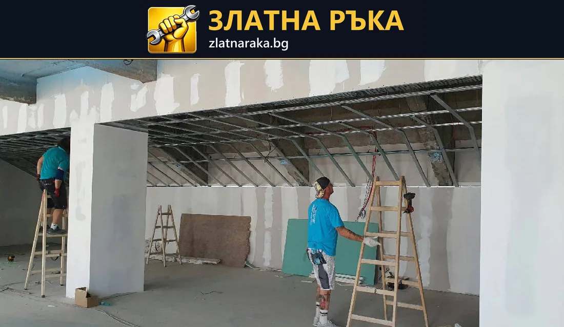 Работници монтират гипсокартонена обшивка около широк отвор; видими профили по тавана.