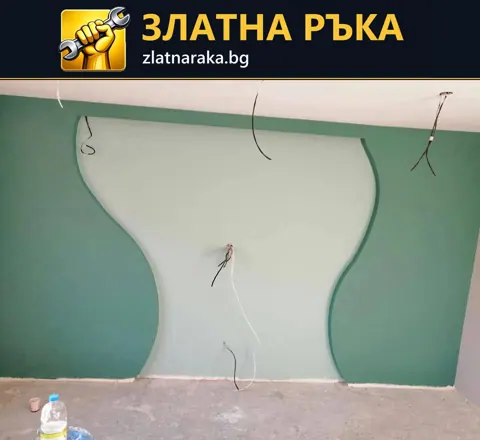 Декоративна стена от гипсокартон с две плавни извивки, зелени странични полета и изведени кабели.
