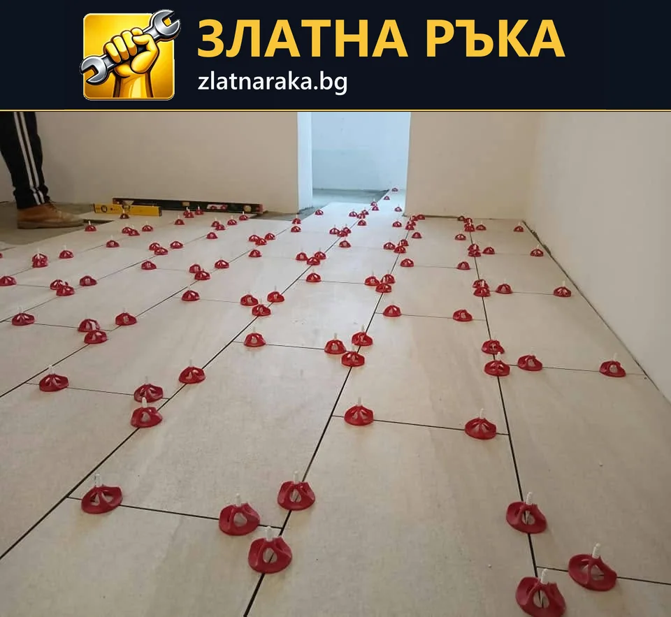 Големи правоъгълни подови плочки са подредени с множество червени нивелиращи елементи по фугите