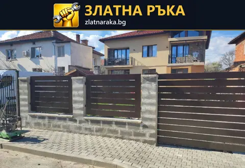 Тъмнокафяви хоризонтални пана и широка дворна врата между светли бетонни стълбове на улична ограда