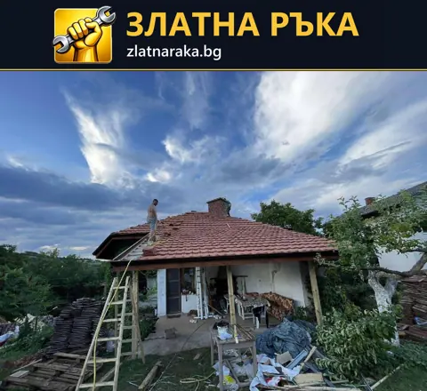 Малка къща с червен многоскатен покрив, стълба до стрехата и строителни материали пред входа