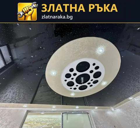 Светъл кръгъл елемент с вградени лампи върху лъскав тъмен таван над огледални врати