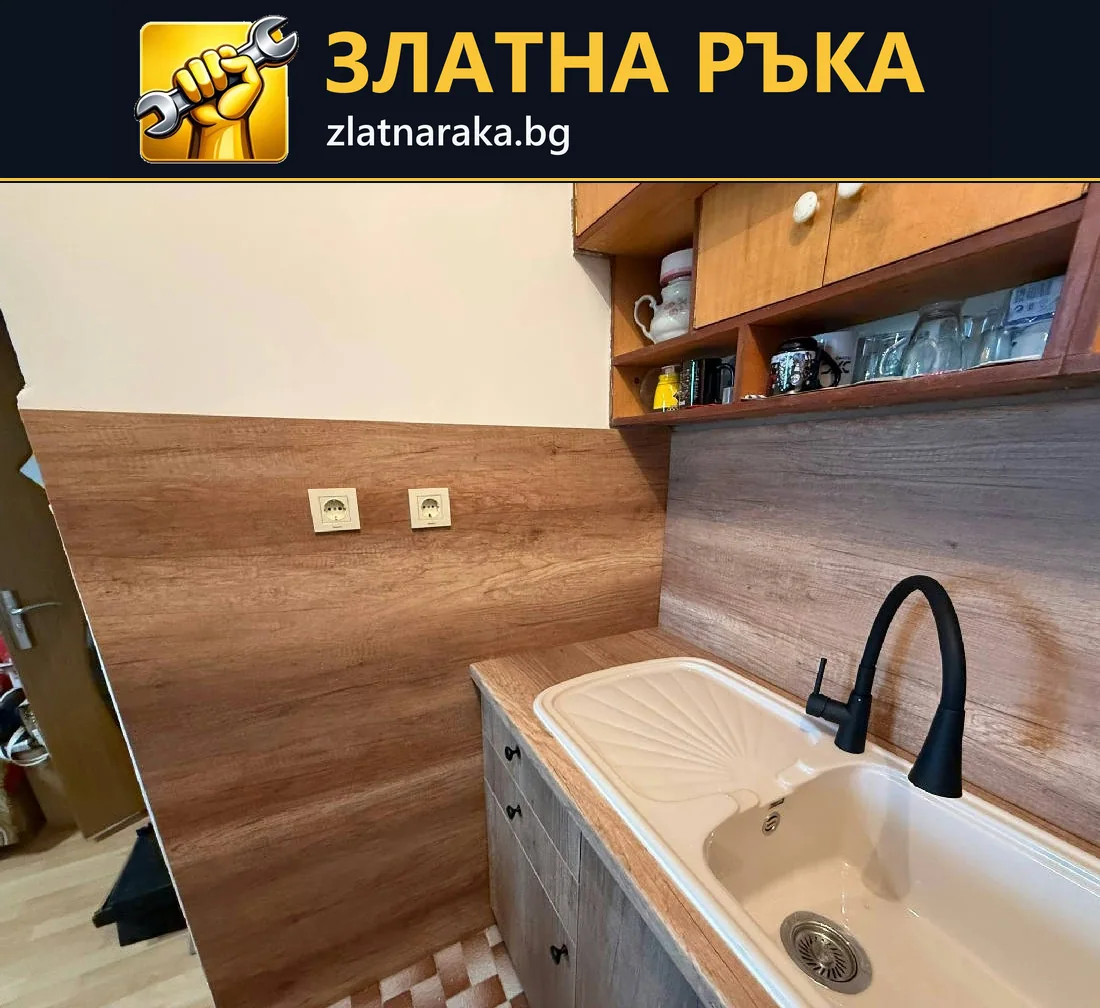Светла мивка с висок черен смесител пред дървесен кухненски гръб и открити горни рафтове
