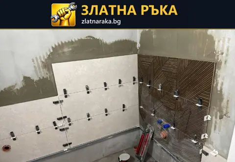 Стенни плочки в процес на монтаж с нивелиращи елементи и тъмен геометричен декор на съседната стена