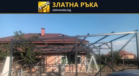 Непокрита метална конструкция с вертикални колони и скатни греди пред къща с червен покрив