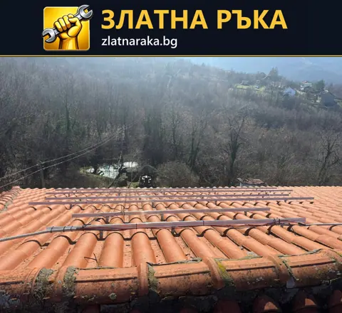 Успоредни метални шини са поставени над редове червени керемиди по скат към горист терен
