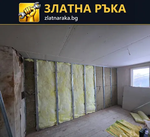 Стая с открити вертикални метални профили и жълта влакнеста изолация по стената под гипсокартонен таван