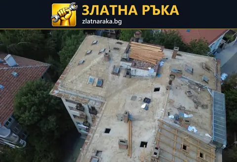 Поглед отгоре към многоъгълен покрив с дъсчена обшивка, няколко комина и оставени строителни материали.