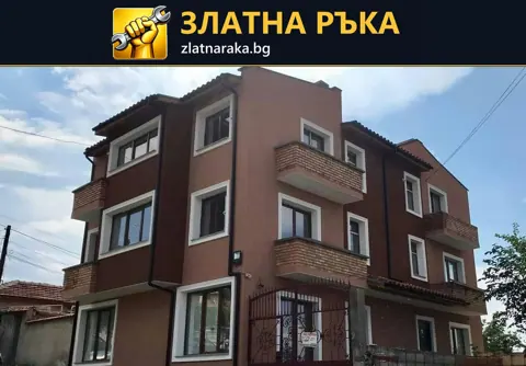 Многоетажна къща с кафяви и светли фасадни полета, бели прозоречни рамки и облицовани балконски чела