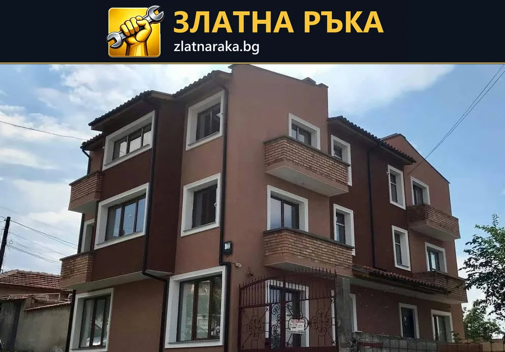 Многоетажна къща с кафяви и светли фасадни полета, бели прозоречни рамки и облицовани балконски чела