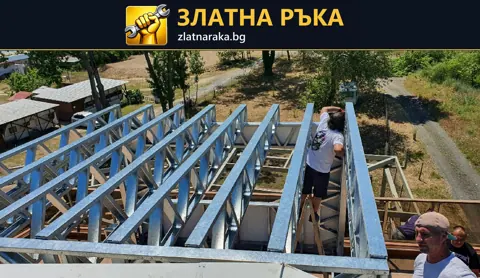 Работници монтират ред светли метални профили върху носеща рамка над малка постройка