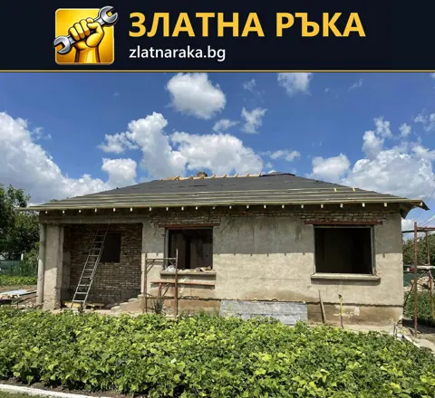 Едноетажна недовършена къща с тъмно покрита покривна основа и открити светли краища на дървени елементи