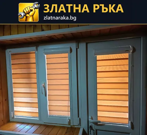 Три оранжеви щори с редуващи се плътни и прозрачни ленти върху синьосива дограма до дървена ламперия