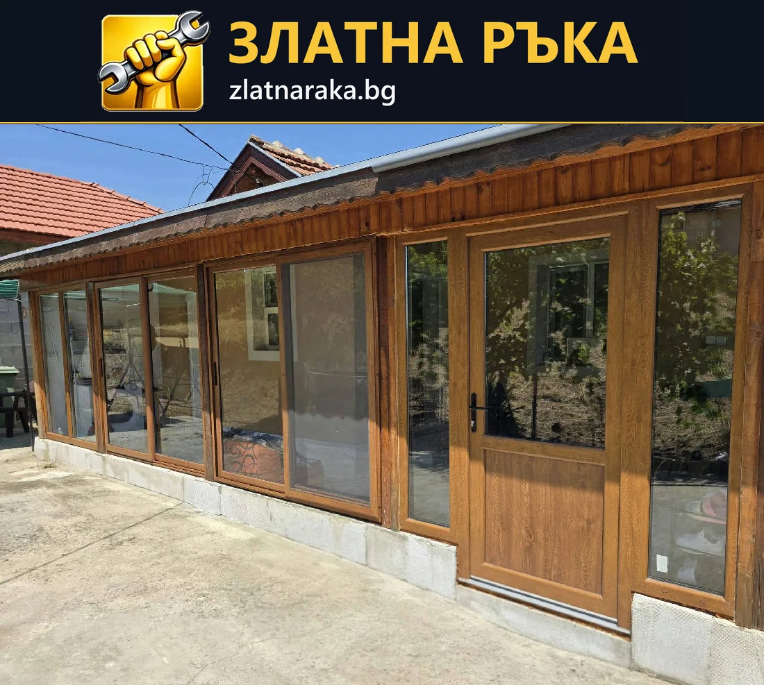 Ред от високи остъклени полета с дървесни рамки по фасадата на ниска пристройка.