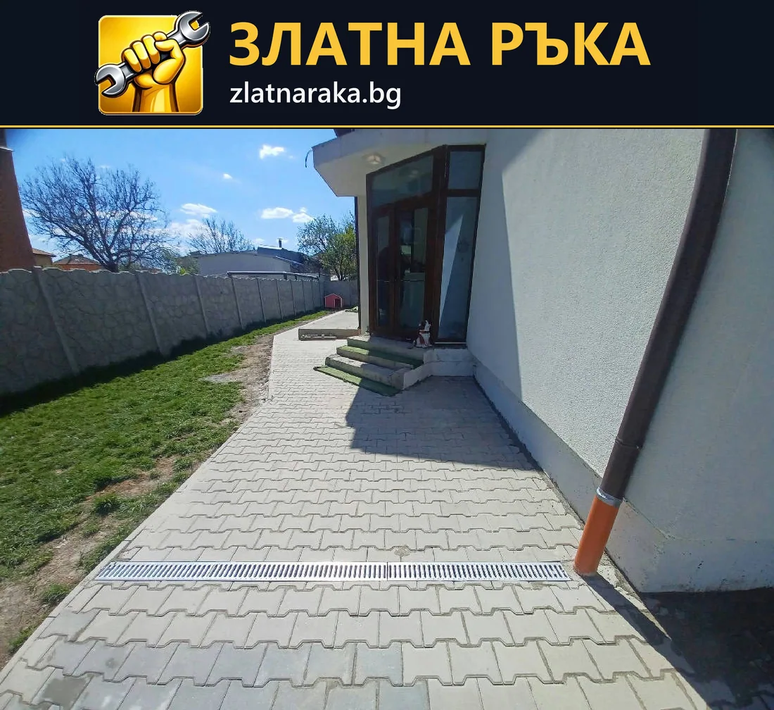 Павирана пътека край къща с линеен отводнител, водосточна тръба и тревна площ.