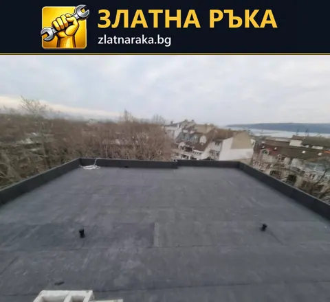 Равна покривна площ с тъмен рулонен слой и нисък периферен борд е заснета над жилищен район