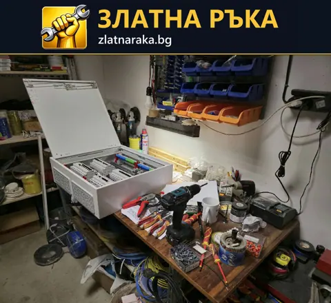 Отворено електрическо табло с редове апарати върху работна маса сред инструменти и проводници.