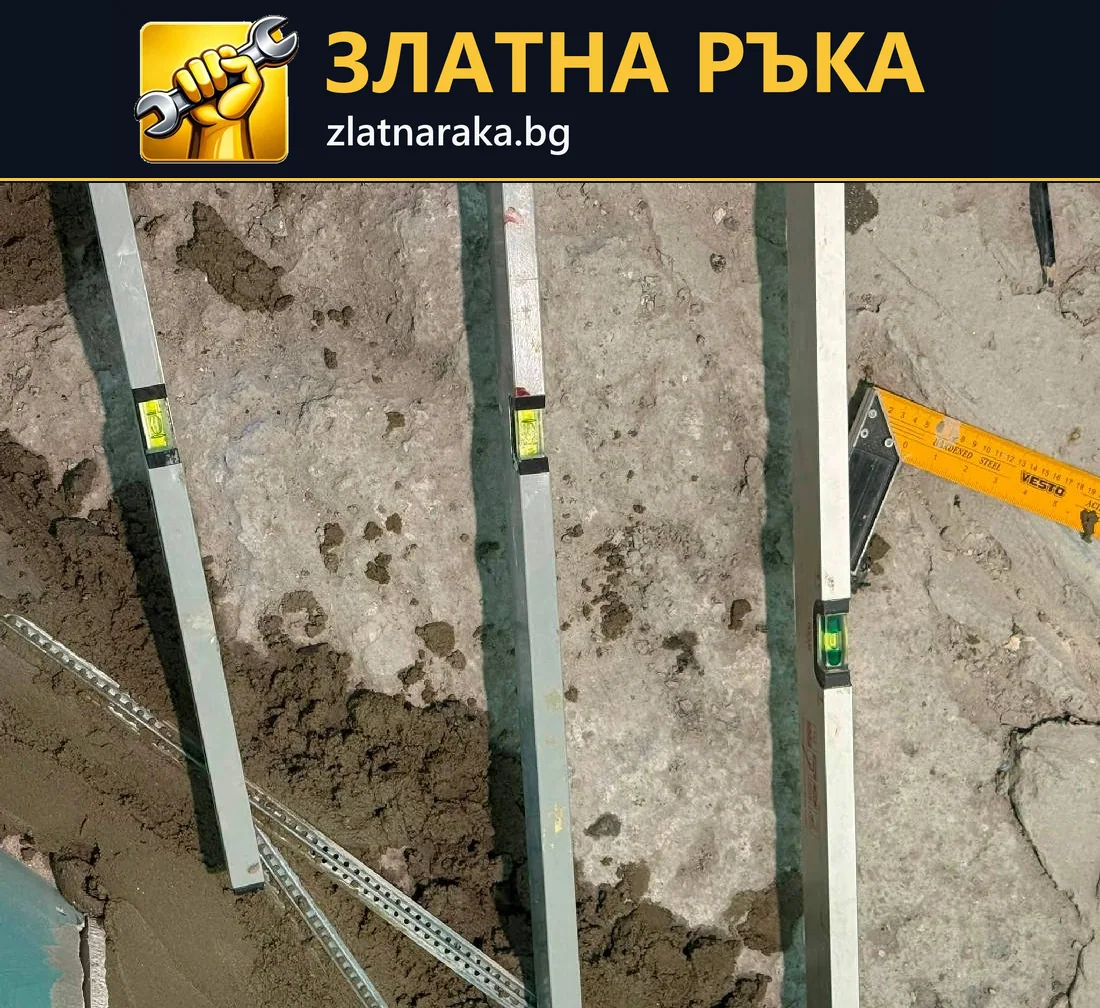 Няколко вертикални метални водача и нивелири са разположени върху неравна разкрита стена преди измазване
