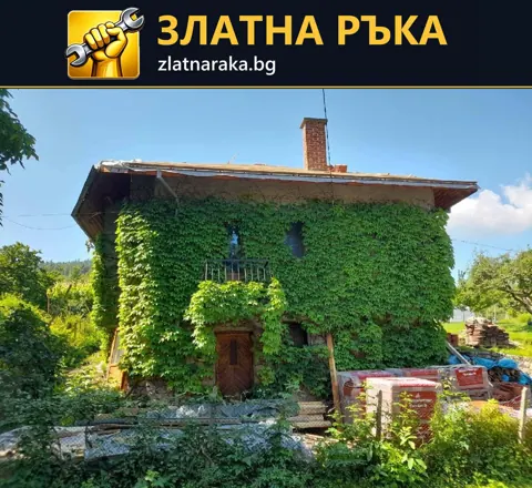 Двуетажна къща с покрита от зеленина фасада и открит покривен етап над широка стреха