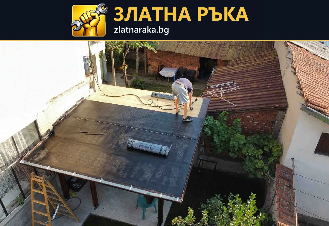 Работник върху плосък дворен навес с частично положено тъмно покритие и руло на покривната площ