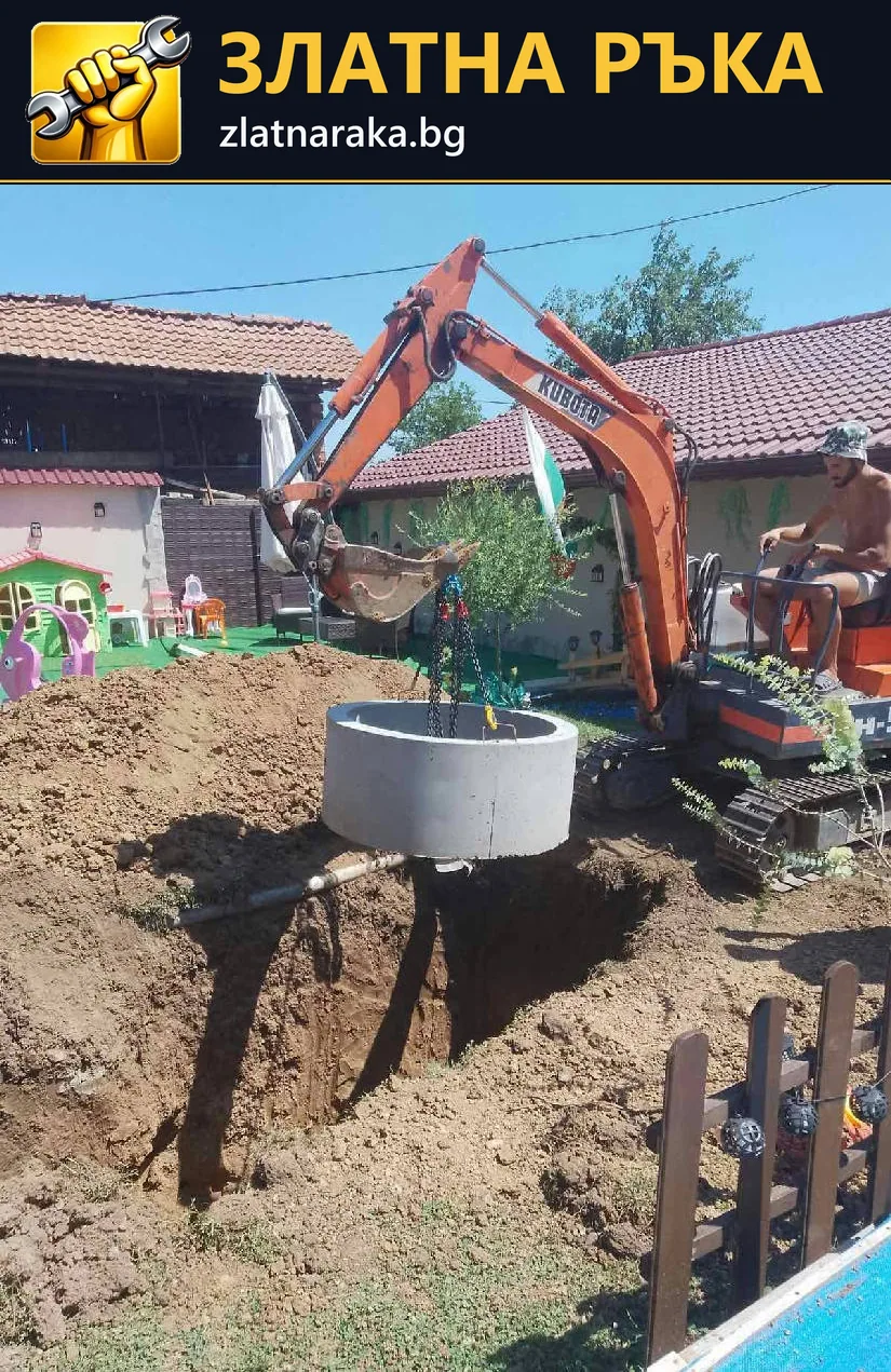 Малък багер държи кръгъл бетонен пръстен над изкоп в двор.