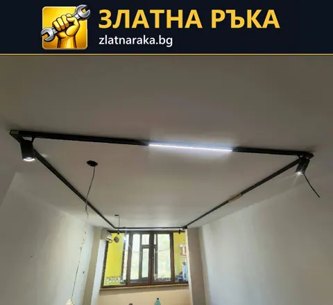 Черни шини по бял таван с включени светлинни участъци и висящи кабели