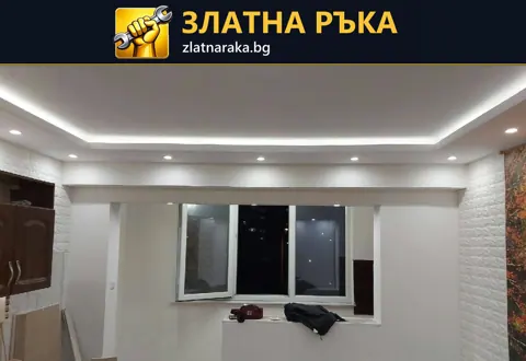 Светеща правоъгълна линия обрамчва центъра на бял окачен таван над прозорец и незавършено помещение