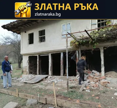 Стара двуетажна къща с разкрити отвори на приземния етаж, строителни отпадъци и хора в двора