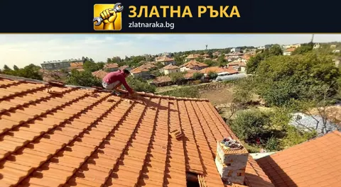 Работник върху червен керемиден покрив до отворен участък и подредени покривни елементи край ската