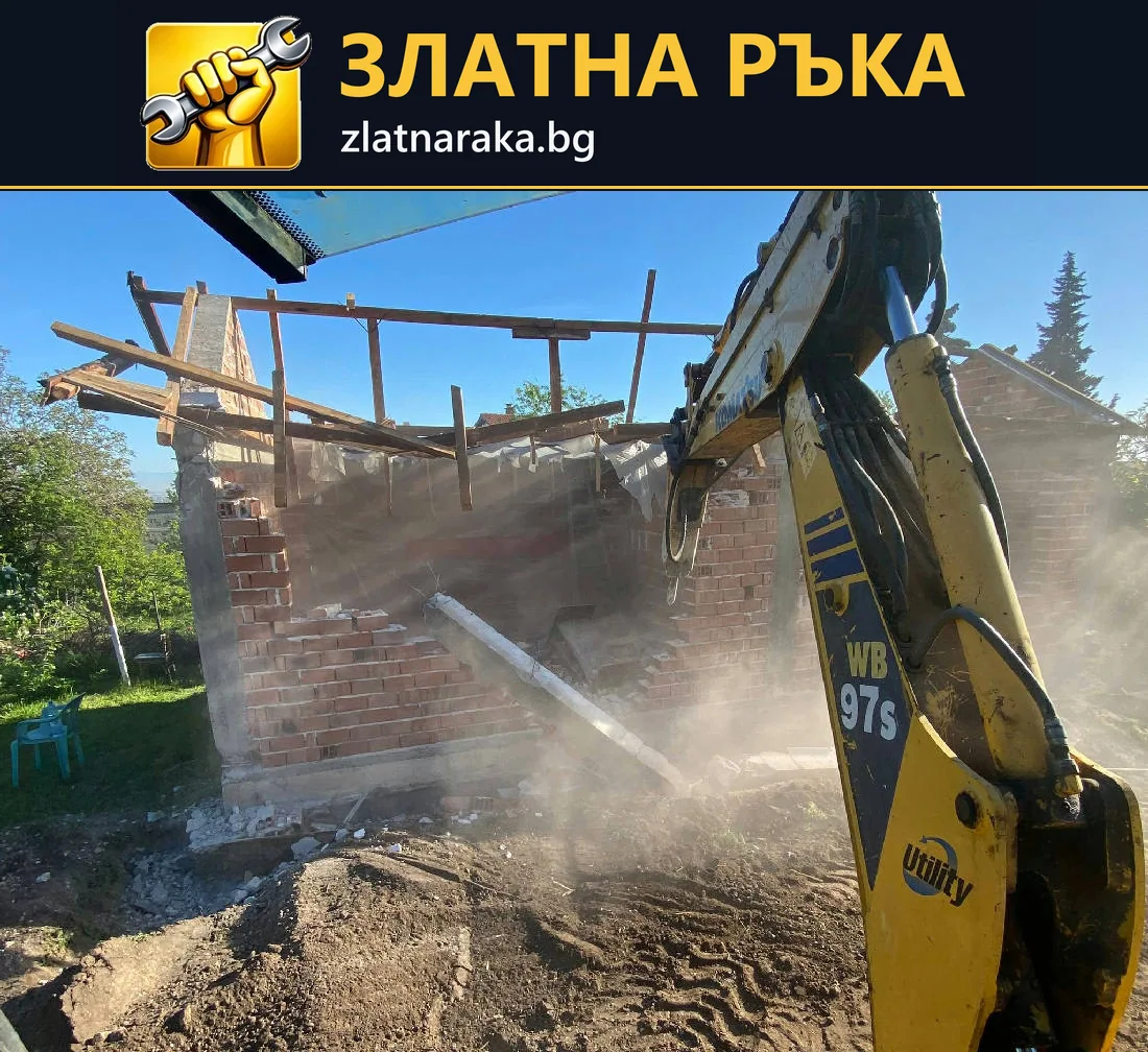 Багер разрушава тухлена стена на постройка с частично свален покрив.