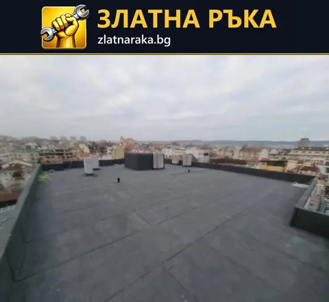 Широк плосък покрив с тъмно рулонно покритие, ниски бордове и няколко излизащи тела