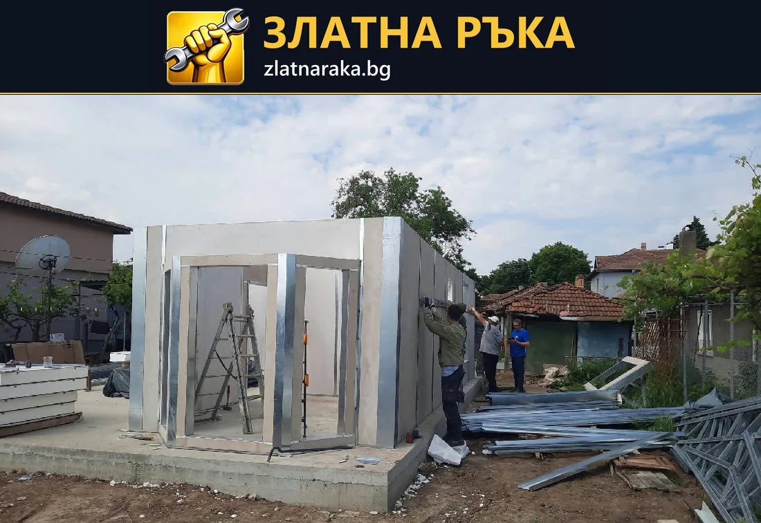 Сглобяване на малка постройка със светли стенни панели и метална рамка върху бетонна основа.