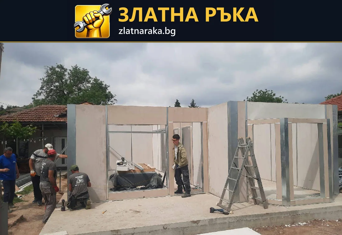 Работници монтират светли стенни панели с оформени врати и прозоречни отвори върху бетонна площадка