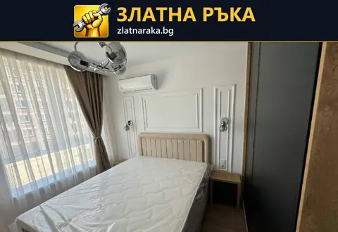 Спалня с висока светла табла, бели декоративни рамки по стената и прозорец с дълги завеси