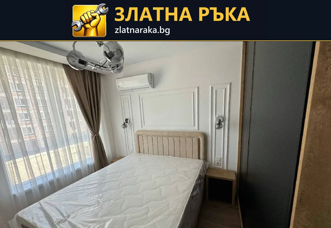 Спалня с висока светла табла, бели декоративни рамки по стената и прозорец с дълги завеси