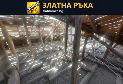 Стара дървена покривна конструкция отвътре с видими пролуки между дъските.