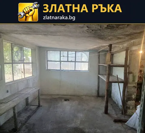 Старо вътрешно помещение преди ремонт с неравни стени, износен таван и множество прозорци.