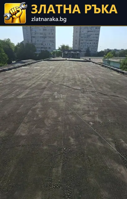 Плосък покрив с потъмняла повърхност, видими снадки и следи от износване пред жилищни блокове